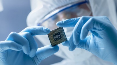 Scientist in personal protective equipment inspecting a computer chip